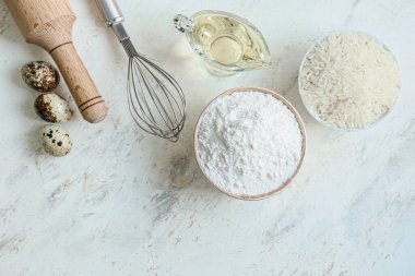 Beyaz masada pirinç unu ve ürünlerle dolu bir kase.