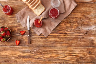 Kavanozlar dolusu lezzetli çilek reçeli ve masada ekmek.