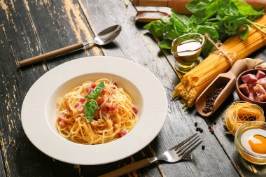 Lezzetli makarna tabağı ve koyu ahşap arka planda malzemeler.