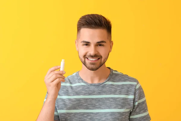 Knappe Jongeman Met Lippenbalsem Kleur Achtergrond — Stockfoto