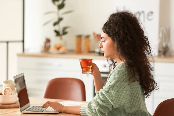 여자가 가정에서 노트북 컴퓨터로 일하면서 뜨거운 마시고 — 스톡 사진