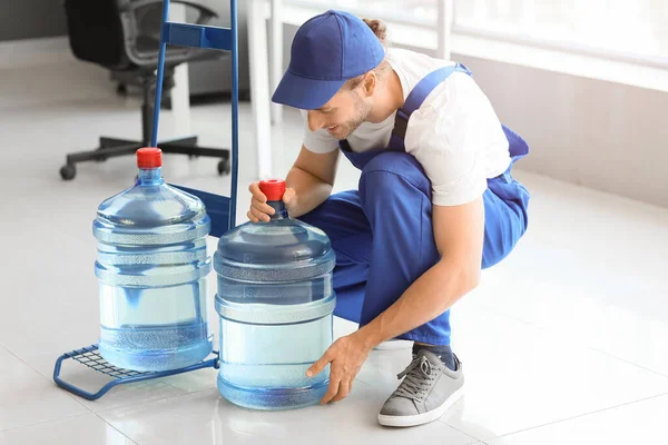 Delivery man with bottles of water in office