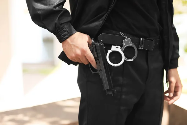 Male police officer with gun outdoors, closeup