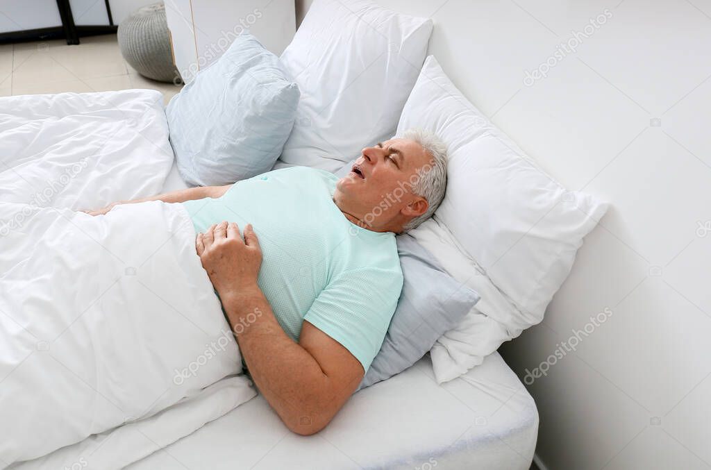 Mature man snoring while sleeping in bed. Apnea problem