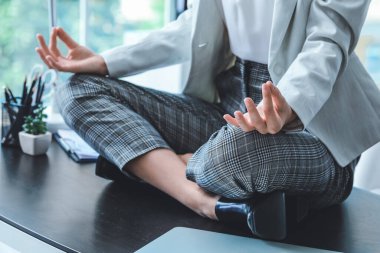 Genç iş kadını ofiste meditasyon yapıyor.