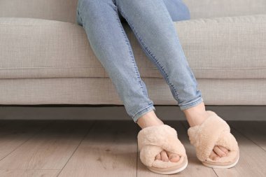 Evdeki koltukta oturan yumuşak terlikli kadın.