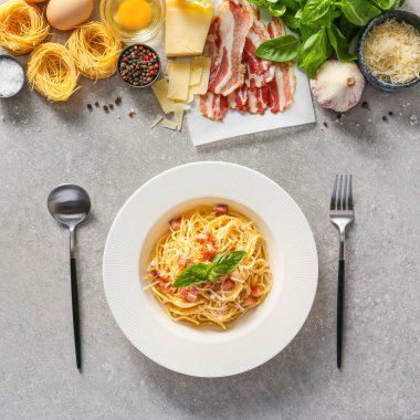 Lezzetli makarna tabağı ve gri arka planda malzemeler.