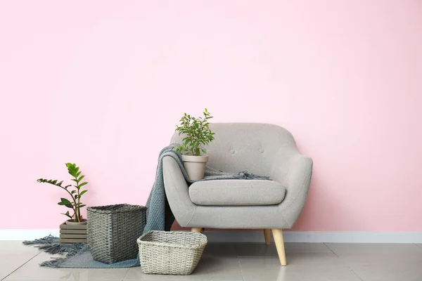 Armchair and wicker baskets with houseplants in room
