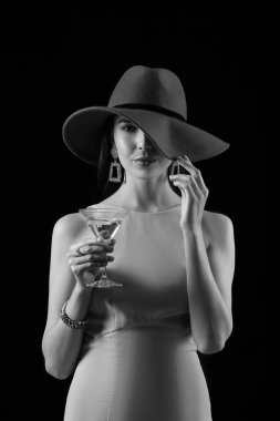 Koyu arkaplanda martini olan güzel bir genç kadın.