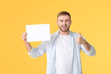 Boş kartı olan genç adam renk arkaplanında başparmağını gösteriyor