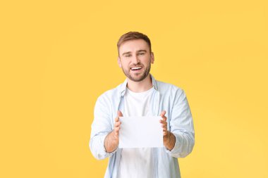 Renk arkaplanı üzerinde boş kartı olan genç adam