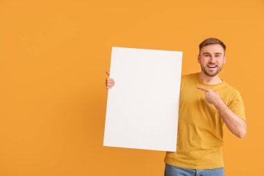 Renkli arka planda boş afişi olan genç adam.