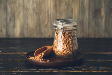 Kavanoz ve kepçeyle masada çiğ mercimek