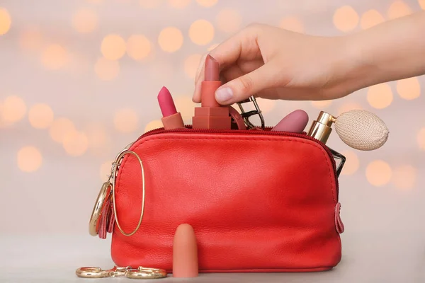 Weibliche Hand Und Tasche Mit Dekorativer Kosmetik Auf Farbigem Hintergrund — Stockfoto