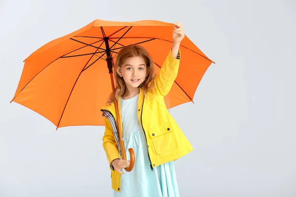 かわいいです女の子でレインコートとととともに傘上のグレーの背景 — ストック写真