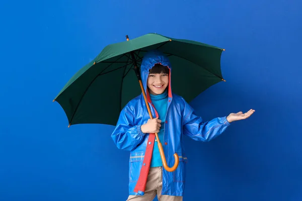 雨のコートと色の背景に傘でかわいい男の子 — ストック写真