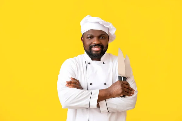 Male African-American chef on color background