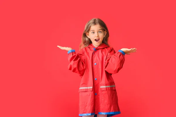 穿着彩色背景雨衣的令人惊讶的小女孩 — 图库照片