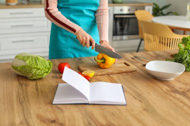 Genç bir kadın mutfakta yemek pişiriyor.