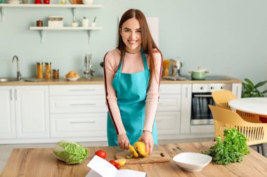 Genç bir kadın mutfakta yemek pişiriyor.