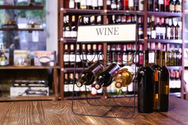 Masasında şarap şişeleri olan bir tutucu.