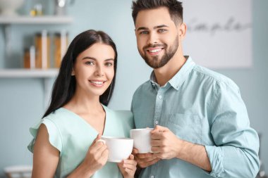 Mutlu genç çift evde çay içiyor.
