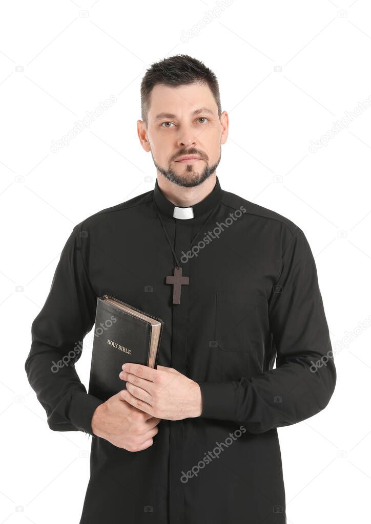 Handsome priest with Bible on white background