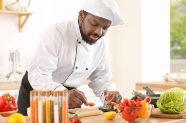 Erkek Afro-Amerikalı aşçı mutfakta yemek pişiriyor.