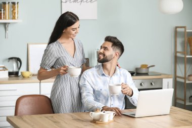 Mutlu genç çift evde çay içiyor.