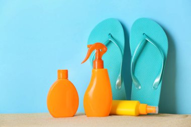 Arka planda parmak arası terlik olan güneş kremi şişeleri