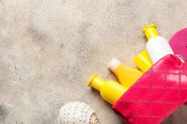 Gri arkaplanda güneş kremi olan çanta