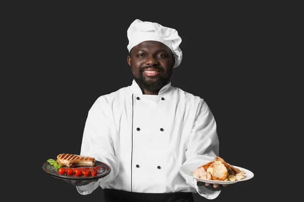 Chef Afroamericano Masculino Con Sabrosos Platos Sobre Fondo Oscuro —  Fotos de Stock