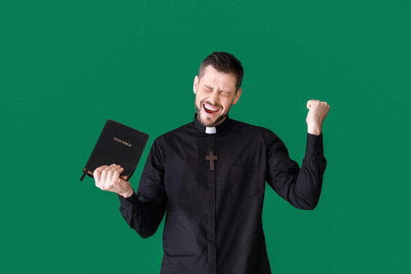 Happy priest with Bible on color background