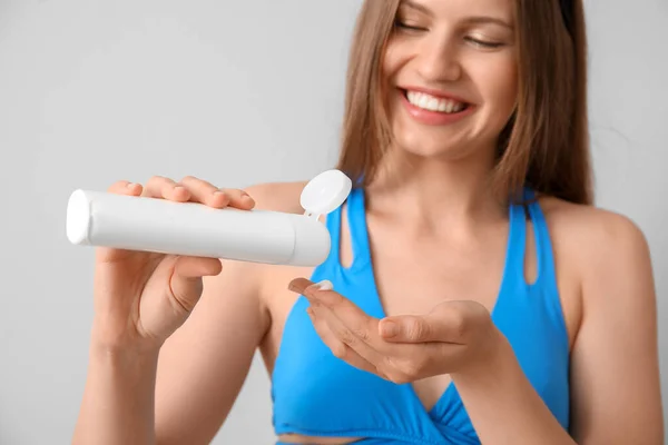Young Woman Applying Sunscreen Cream Light Background — Stock Photo, Image