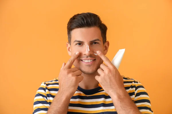 Young Man Applying Sunscreen Cream Color Background — Stock Photo, Image