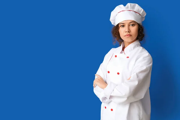 Female African-American chef on color background