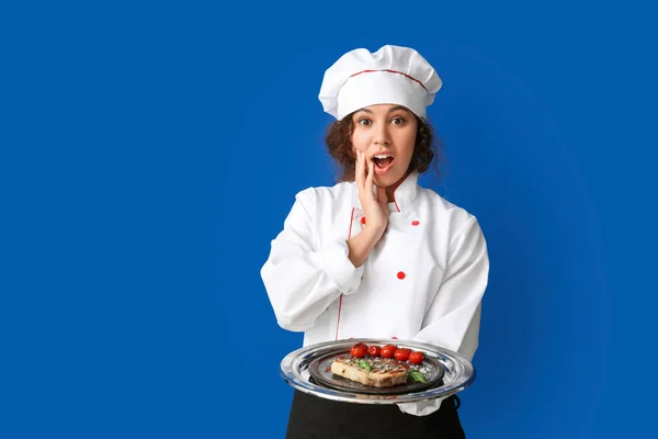 Female African-American chef with tasty dish on color background