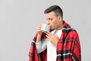 Gri arka planda çay fincanı olan yakışıklı genç adam.