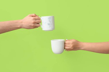 Arka planda sıcak kahve fincanları olan eller.