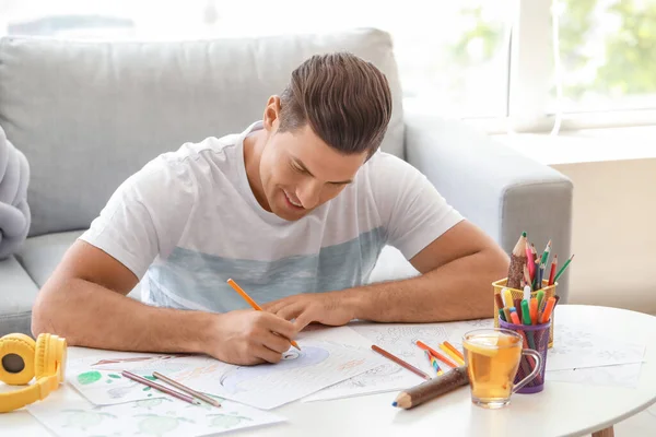 Young man coloring pictures at home