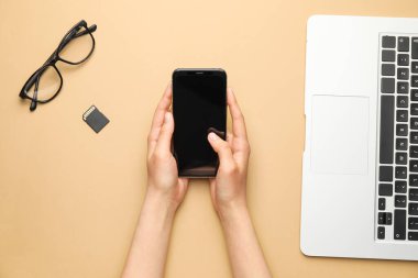 Renkli arka planda modern dizüstü bilgisayarı ve cep telefonu olan kadın elleri