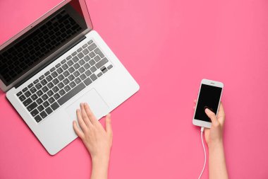 Renkli arka planda modern dizüstü bilgisayarı ve cep telefonu olan kadın elleri