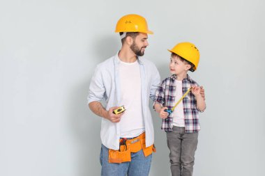 Gri arka planda mezuraları olan baba ve oğul.