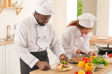 Afro-Amerikalı aşçılar mutfakta yemek pişiriyor.