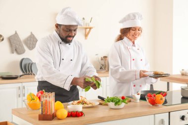 Afro-Amerikalı aşçılar mutfakta yemek pişiriyor.