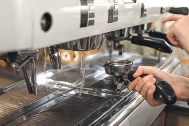 Kafede kahve yapan genç barista, yakın plan.