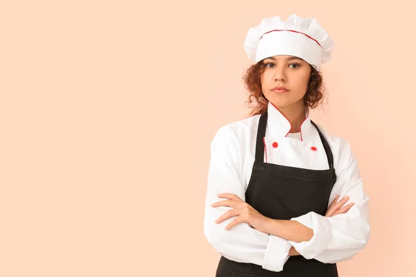 Female African-American chef on color background