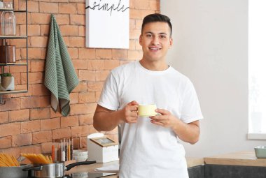 Evde çay içen yakışıklı genç adam.