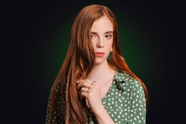 Beautiful young redhead woman on dark background