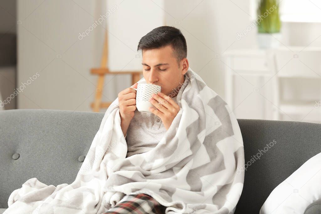 Ill young man drinking tea at home